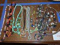 Full view of multiple costume jewelry pieces spread out on a surface including various necklaces, beads, and pendants.