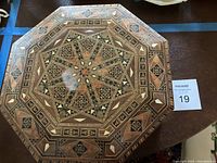 Top view of the octagonal wooden box showing the intricate marquetry patterns with geometric star designs and mother of pearl inlays.
