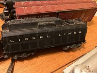 Close-up photo of a black Lionel locomotive tender marked 'LIONEL LINES' and reddish-brown boxcar labeled 'MINNEAPOLIS & ST LOUIS'