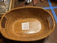 Top-down view inside the Nantucket basket showing woven construction and wooden base with auction label indicating measurements 14x10x5.