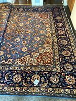 Full view of the Persian hand knotted Mashad wool carpet showing floral motifs and large blue border.