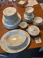 Theodore Haviland Festival porcelain dinnerware showing stacked plates, cups, saucers, creamer and sugar bowl with lid on a wooden table.