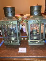 Front view of both brass Viking hurricane lamps side by side