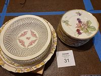 Photo showing stacked plates and trellis bowl with floral designs, including gold trim and intricate lattice sides on bowl.