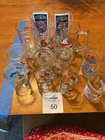 Top-down view showing all 11 collectible vintage glasses with various cartoon and branded decals arranged on a table.