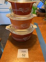 Overall view of three stacked vintage Pyrex covered casseroles showing the color and wheat design.