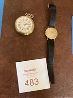 Photo showing two watches on brown surface, one pocket watch and one wristwatch with leather strap.