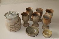 Assorted brown pottery: jar with lid, six goblet-style cups, two small bowls