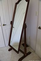 Full-length cheval mirror angled side view showing solid wood frame and standing support.