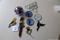 Photo of all five window suncatchers and one decorative glass ball arranged on a flat surface.