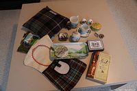 Wide shot showing all items included in the lot arranged on a table, with textiles, ceramics, jewelry, a decorative tray, and a book visible.