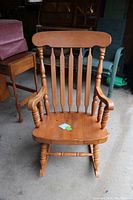 Front view of maple rocking chair showing spindle backrest and curved armrests.