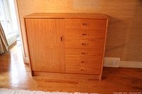 Full view of teak veneer sideboard showing cabinet door on left and six drawers on right, placed on wood floor near window.