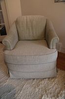 Front view of the sage green Vogel swivel armchair showing cushioned seat, rolled arms, and skirted base.