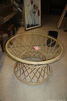 Photo of round wicker and glass low table with circular wicker base and glass top, showing clear construction and natural wicker color.