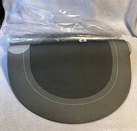 Two new oval rubber floor mats, one partially rolled and wrapped in plastic, showing top surface oval design and size.