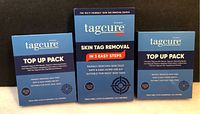 Front of three Tagcure boxes showing one skin tag removal device and two top up packs.