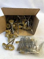 Open box containing multiple wire brush attachments for rotary tools, some loose and some in plastic bags