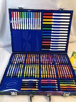 Opened art kit showing assorted colored crayons, colored pencils, and markers neatly arranged inside the travel case.