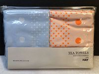 Front view of two tea towels in original packaging showing big dot patterns and label with brand HAY and designers Scholten & Baijings.
