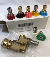 Pressure washer brass coupler with seven nozzles of varying colors lined on box edge