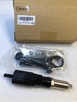 Box with label and sealed plastic bag containing rivet gun drill adapter and accessories.