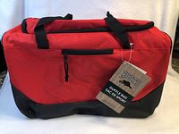 Red Roots duffle bag with black bottom, main zipper, front zippered pocket, and attached tag.