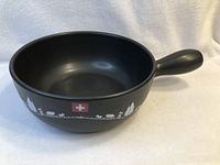 Black SwissMar fondue pot side view showing Swiss landscape decorations and handle.
