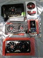 Four graphics cards laid out on surface with NVIDIA box and AMD driver discs