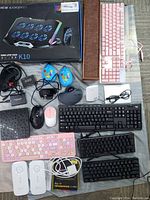 Full lot overview with all visible items including cooling pad box, pink keyboard, multiple mice, headphones, black keyboards, WiFi extenders, and memory module.