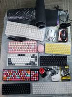 Wide shot of all items on floor: 7 keyboards, 3 mice, 2 web cameras, 3 RGB pads, black mats, network extenders and cables, portable DVD unit