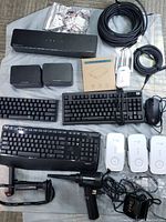 Overview of lot including keyboards, network devices, cables, and accessories on fabric.