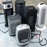 Photo showing seven ceramic tower heaters in varied sizes and shapes with cords for power testing.