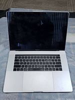 Top view of opened MacBook Pro A1990 with black keyboard and screen shown, device does not power on or boot as per seller.