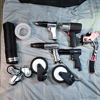 Full lot overview of pneumatic tools, caster wheels, flexible hose, and tape on a fabric
