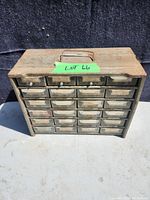 Front view of rusted 24-drawer metal hardware bin, drawers closed showing overall condition and size.