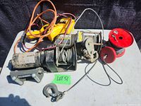 Photo of the used electric winch with steel cable, hook, control wires, red snatch block, and fairlead on a table surface