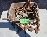 Large plastic bin filled with multiple cast iron gate hooks and eyes, heavily rusted, some attached to rods or bars.