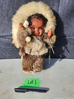 Front view of the vintage indigenous doll wearing handmade fur parka, mittens, and pants showing details of face and clothing.
