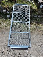 Full length view of steel loading ramp showing metal mesh surface and frame placement.
