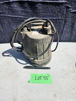 Front view of used submersible sump pump showing cylindrical body, power cord, and outlet fitting.