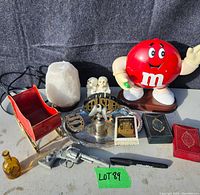Full view of all vintage items on display including M&M figure, salt and pepper shakers, playing cards, revolver figurine, amber bottle, silver eagle figurine, red sleigh, and salt lamp.