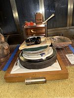 Photo showing stacked ashtrays including black Disneyland ashtray, leather encased and duck designed, plus containers and a shell