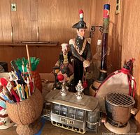 Full view of the lot showing trolley car decanter holder with decanters, ceramic figurine, coconut cup with swizzle sticks, and hibachi front and center