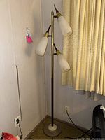 Full view of the vintage floor lamp with three glass sconces and tall metal stand with round base.