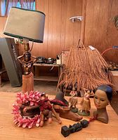 Overview of all items: table lamp, straw shade, hula figurines, busts, shoe form, lei.