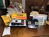 Kodak Instamatic 20 camera, Magicube extender box, View-Master viewer, and View-Master disks arranged on a table