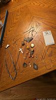Four necklaces including three gold-tone and one silver-tone with multiple pendants laid out on a wooden table.