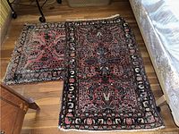 Two rectangular oriental rugs side by side on wooden floor showing wear and missing fringes