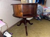 Side view of the wood swiveling side table showing the inlay on the side panel and the tripod base.